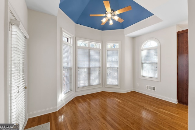 empty room featuring baseboards, a ceiling fan, wood finished floors, and visible vents