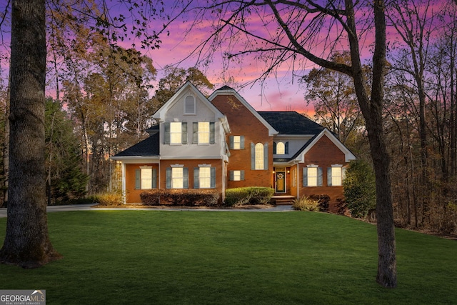 traditional home featuring a lawn and brick siding