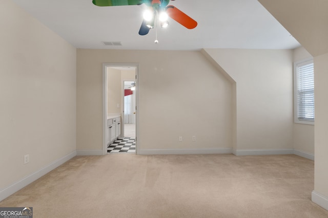 additional living space featuring light colored carpet, a ceiling fan, baseboards, and visible vents