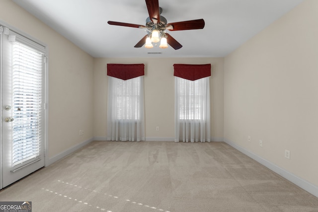 spare room featuring a healthy amount of sunlight, carpet, a ceiling fan, and visible vents