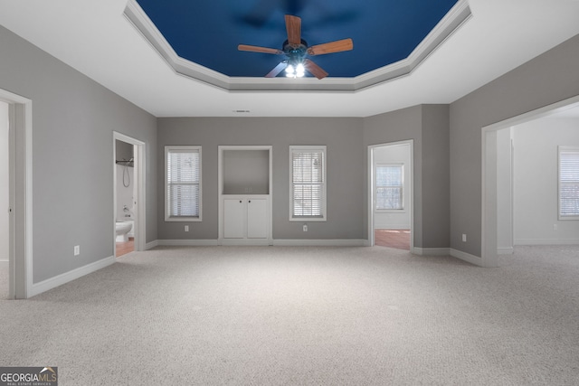 unfurnished bedroom with a raised ceiling, baseboards, carpet flooring, and connected bathroom