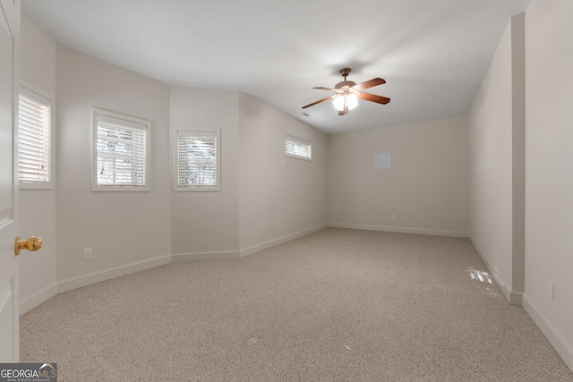 carpeted spare room with ceiling fan and baseboards