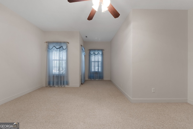 carpeted empty room featuring a ceiling fan and baseboards