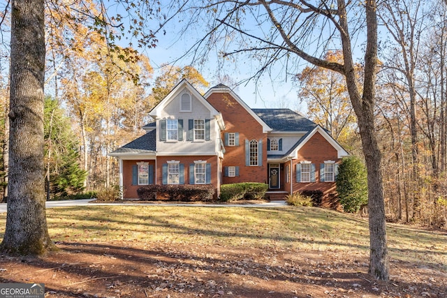 view of front facade with brick siding and a front lawn