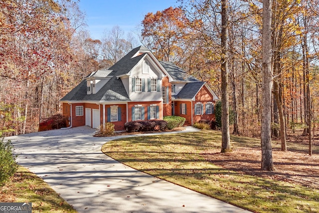 traditional-style home with driveway, brick siding, a front lawn, an attached garage, and a shingled roof