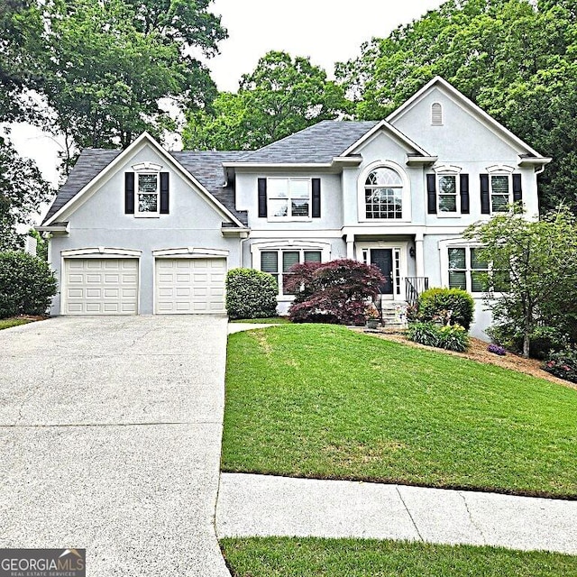 view of front of house with driveway, a shingled roof, a front yard, and stucco siding