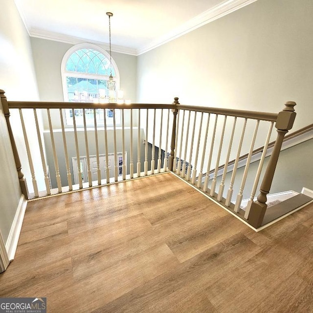 stairs with crown molding, baseboards, wood finished floors, and a chandelier