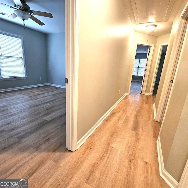 hall featuring baseboards, visible vents, wood finished floors, and attic access