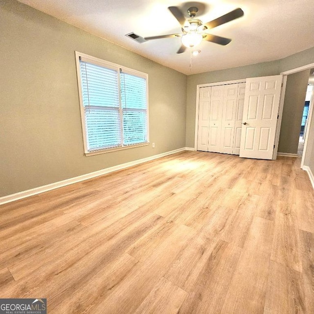 unfurnished bedroom featuring baseboards, visible vents, light wood finished floors, and a closet