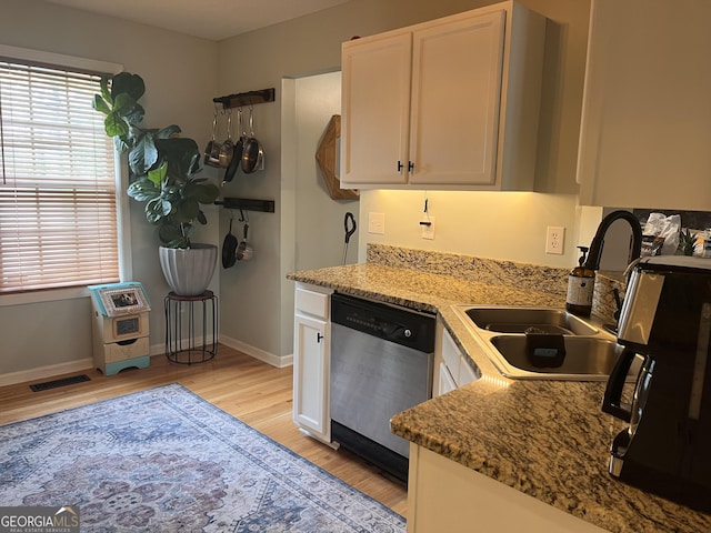 kitchen featuring stainless steel dishwasher, plenty of natural light, light wood-type flooring, white cabinetry, and a sink