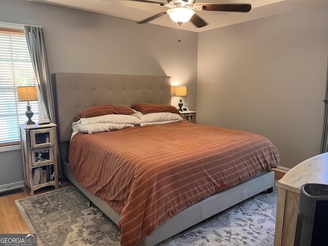 bedroom with baseboards, ceiling fan, light wood-style flooring, and visible vents