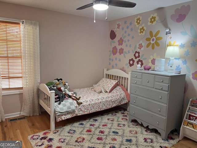 bedroom with visible vents, wood finished floors, and multiple windows