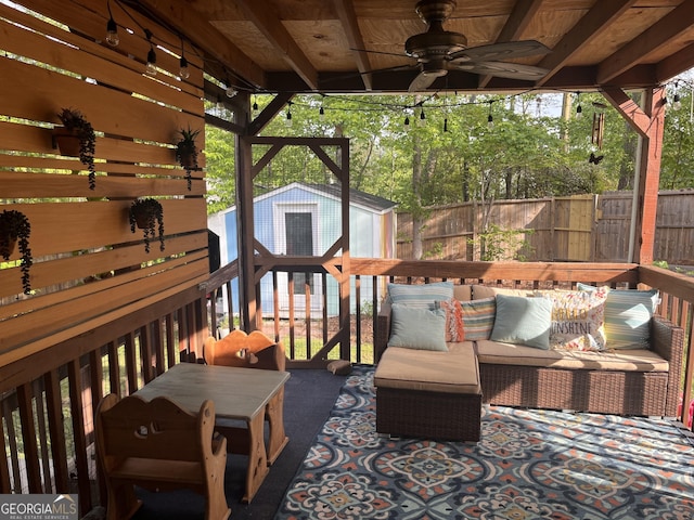 wooden terrace featuring a fenced backyard, a storage unit, ceiling fan, and an outdoor living space