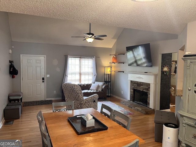 dining room featuring lofted ceiling, light wood-style floors, baseboards, ceiling fan, and a textured ceiling