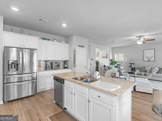 kitchen featuring visible vents, appliances with stainless steel finishes, a sink, open floor plan, and light wood-style floors