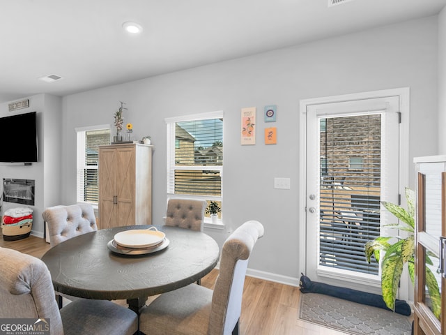 dining area featuring baseboards, visible vents, light wood finished floors, and a wealth of natural light