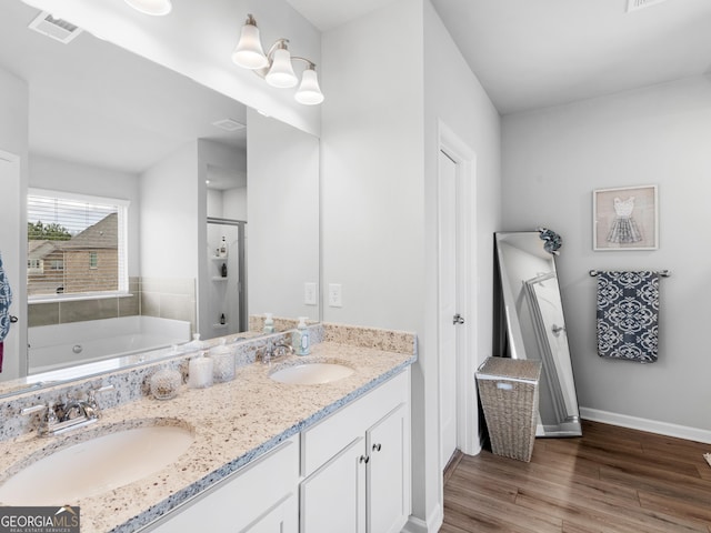 full bathroom featuring a stall shower, baseboards, a sink, and wood finished floors