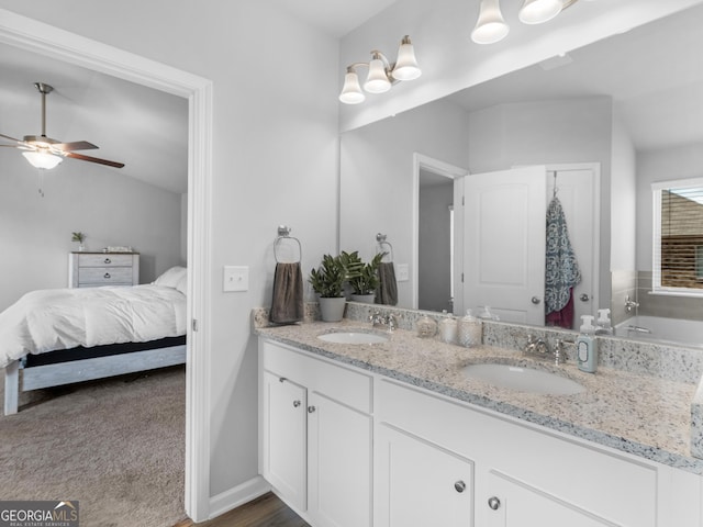 ensuite bathroom with double vanity, a ceiling fan, a sink, and ensuite bath