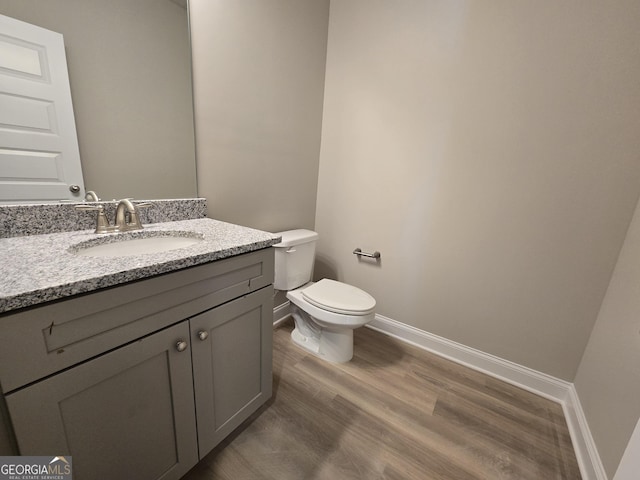 bathroom with vanity, baseboards, wood finished floors, and toilet