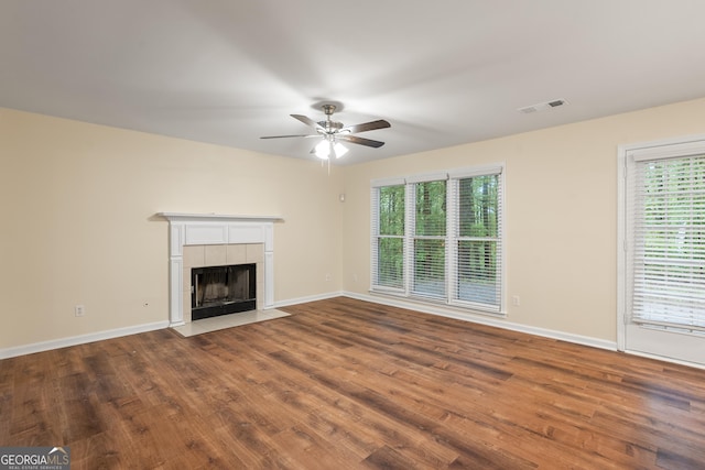 6939 Waters Edge Dr, Stone Mountain, GA 30087 - unfurnished living room with dark wood-style flooring, a tiled fireplace, a ceiling fan, baseboards, and visible vents