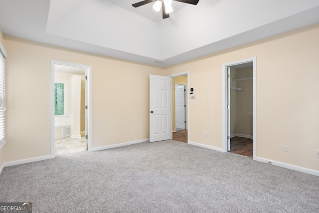 6939 Waters Edge Dr, Stone Mountain, GA 30087 - unfurnished bedroom with baseboards, a spacious closet, ensuite bathroom, carpet, and a tray ceiling