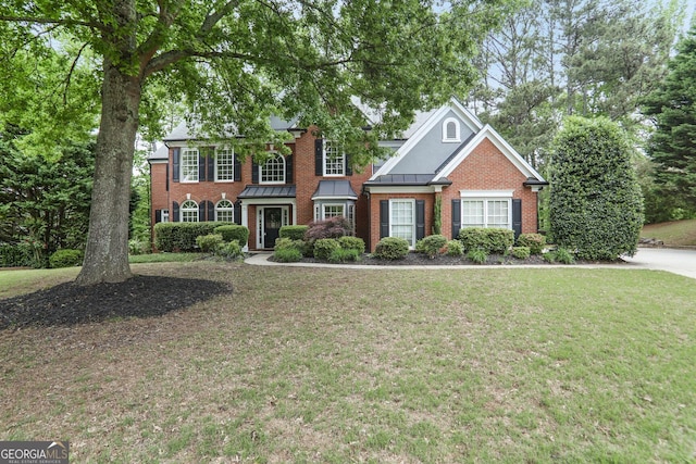 colonial house featuring brick siding, a front yard, and a standing seam roof