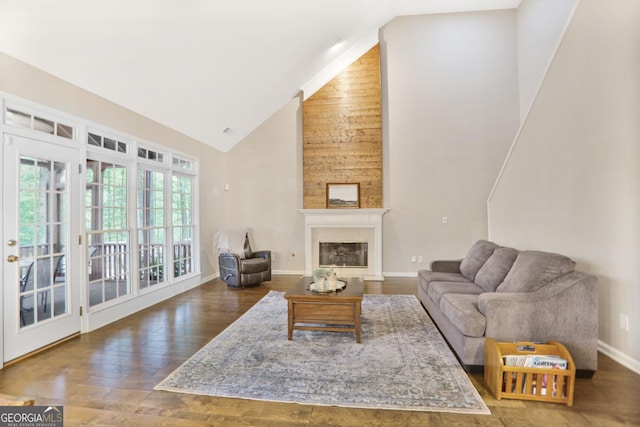 living room with high vaulted ceiling, a glass covered fireplace, baseboards, and wood finished floors