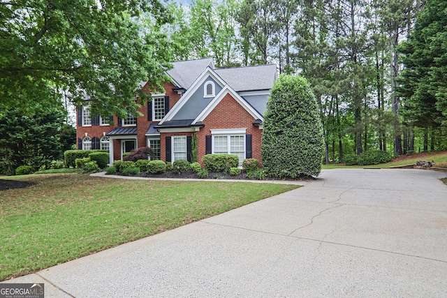view of front facade featuring concrete driveway, brick siding, a shingled roof, and a front lawn
