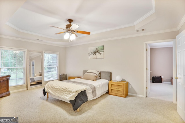 carpeted bedroom featuring visible vents, crown molding, baseboards, a tray ceiling, and a ceiling fan