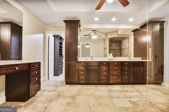 bathroom featuring a raised ceiling, double vanity, a ceiling fan, baseboards, and a shower stall