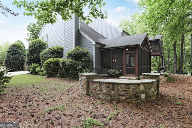 view of side of home featuring a sunroom and a shingled roof