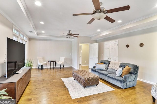 living area with visible vents, ornamental molding, baseboards, a ceiling fan, and light wood finished floors