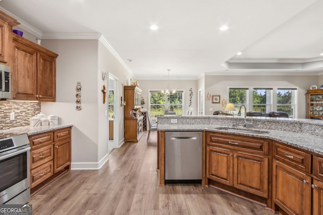 kitchen featuring a notable chandelier, tasteful backsplash, a sink, stainless steel appliances, and light wood-type flooring