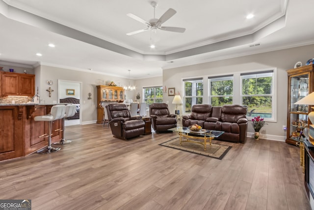 living area featuring baseboards, recessed lighting, a tray ceiling, light wood finished floors, and ceiling fan with notable chandelier