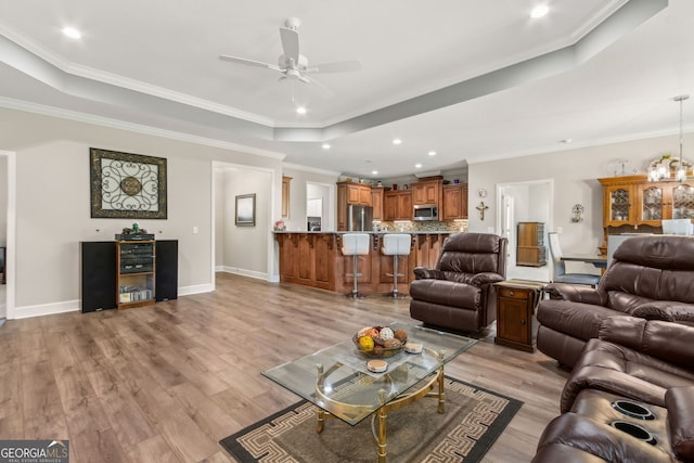 living area featuring light wood-style floors, baseboards, recessed lighting, a raised ceiling, and a ceiling fan