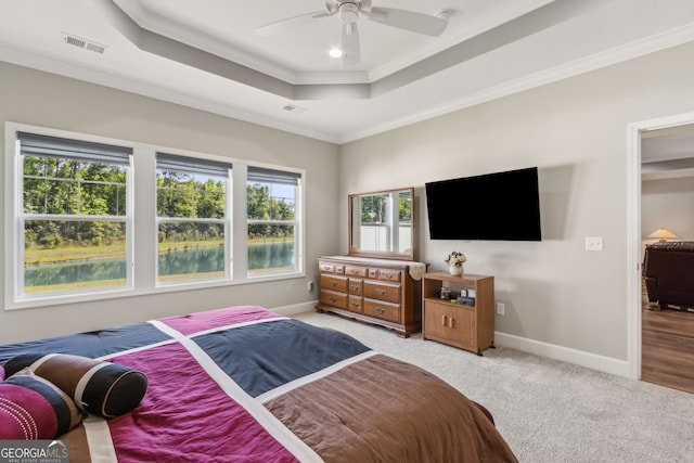 carpeted bedroom featuring baseboards, visible vents, ornamental molding, and a raised ceiling