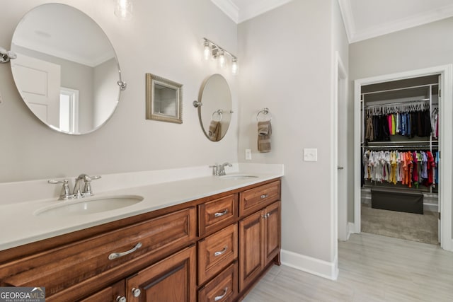 bathroom featuring crown molding, double vanity, baseboards, and a sink