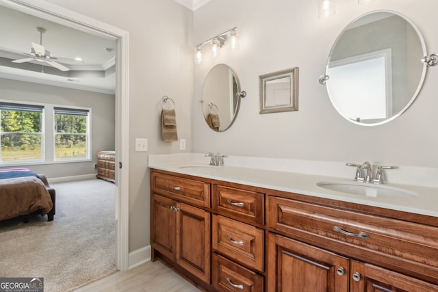 ensuite bathroom featuring a sink, baseboards, crown molding, and ceiling fan