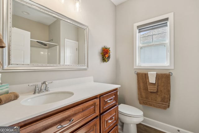 bathroom featuring vanity, walk in shower, and toilet