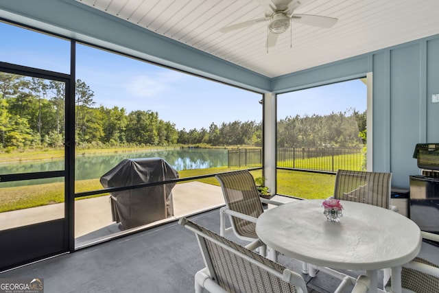 sunroom / solarium with a water view, ceiling fan, and outdoor dining space
