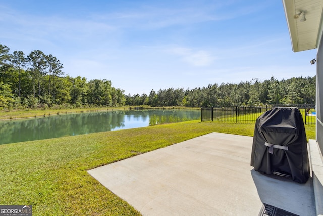 view of patio with a water view, fence, and a wooded view