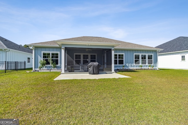 back of house featuring a sunroom, board and batten siding, a yard, and a patio