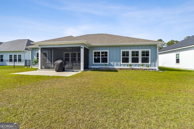 back of house with a lawn, board and batten siding, a sunroom, and a shingled roof