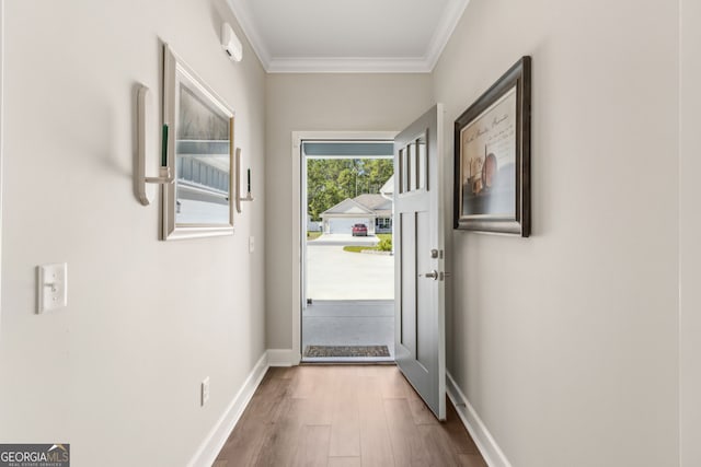 doorway featuring baseboards, ornamental molding, and wood finished floors