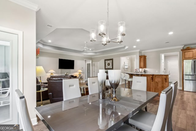 dining space with recessed lighting, ornamental molding, ceiling fan with notable chandelier, and wood finished floors