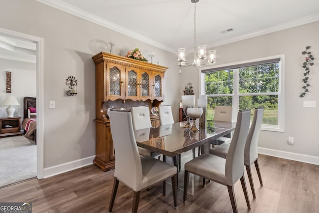 dining room with visible vents, crown molding, wood finished floors, baseboards, and a notable chandelier