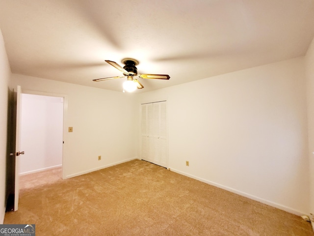 spare room featuring baseboards, a ceiling fan, and light carpet
