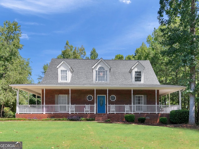 farmhouse-style home with covered porch, brick siding, a shingled roof, and a front yard
