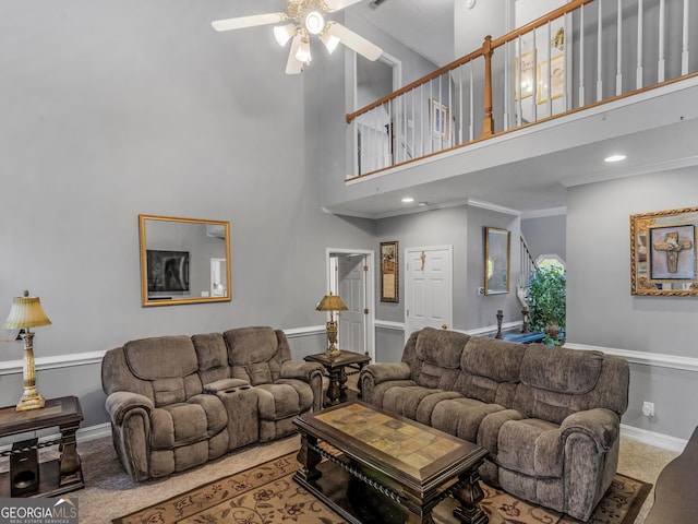 living room featuring ceiling fan, ornamental molding, baseboards, and a towering ceiling