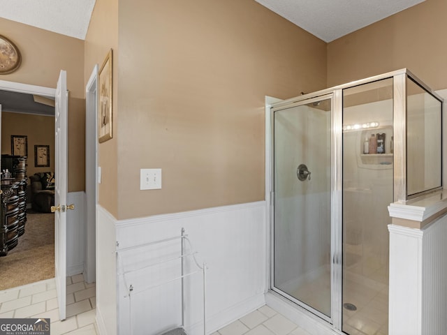 bathroom with a wainscoted wall, tile patterned flooring, and a stall shower